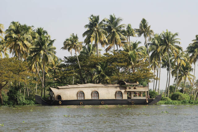 Ein traditionelles Hausboot liegt am Ufer in den Backwaters Südindiens